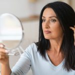Mature woman checking her face in mirror