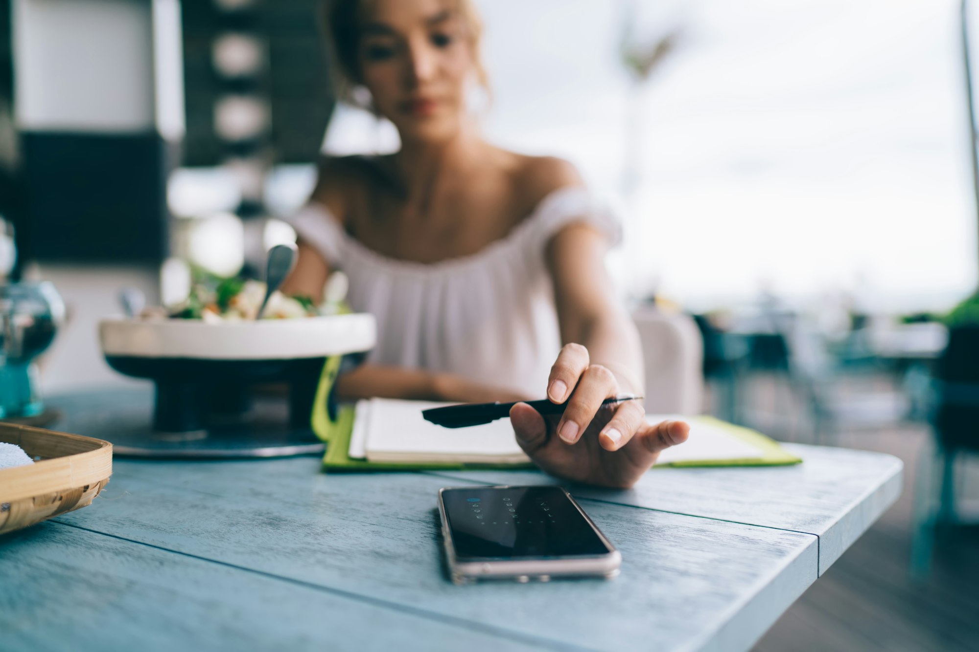 Blurred woman using smartphone in cafe having lunch