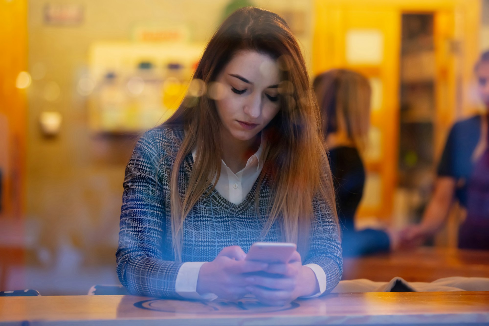 girl with a mobile phone in a cafe, side view