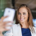 Smiling brunette woman holding cell phone