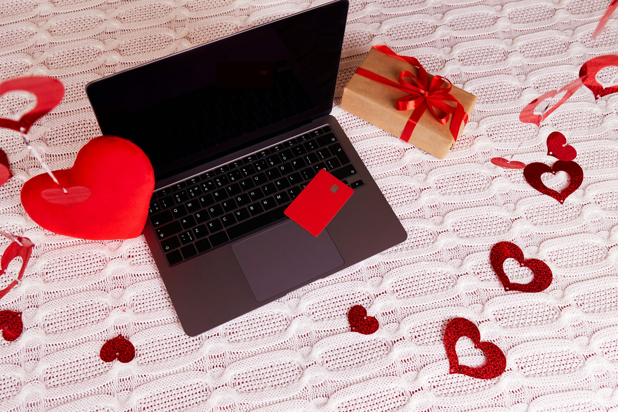 Shopping online for Valentine's Day. Laptop, credit card, gift, decor, hearts