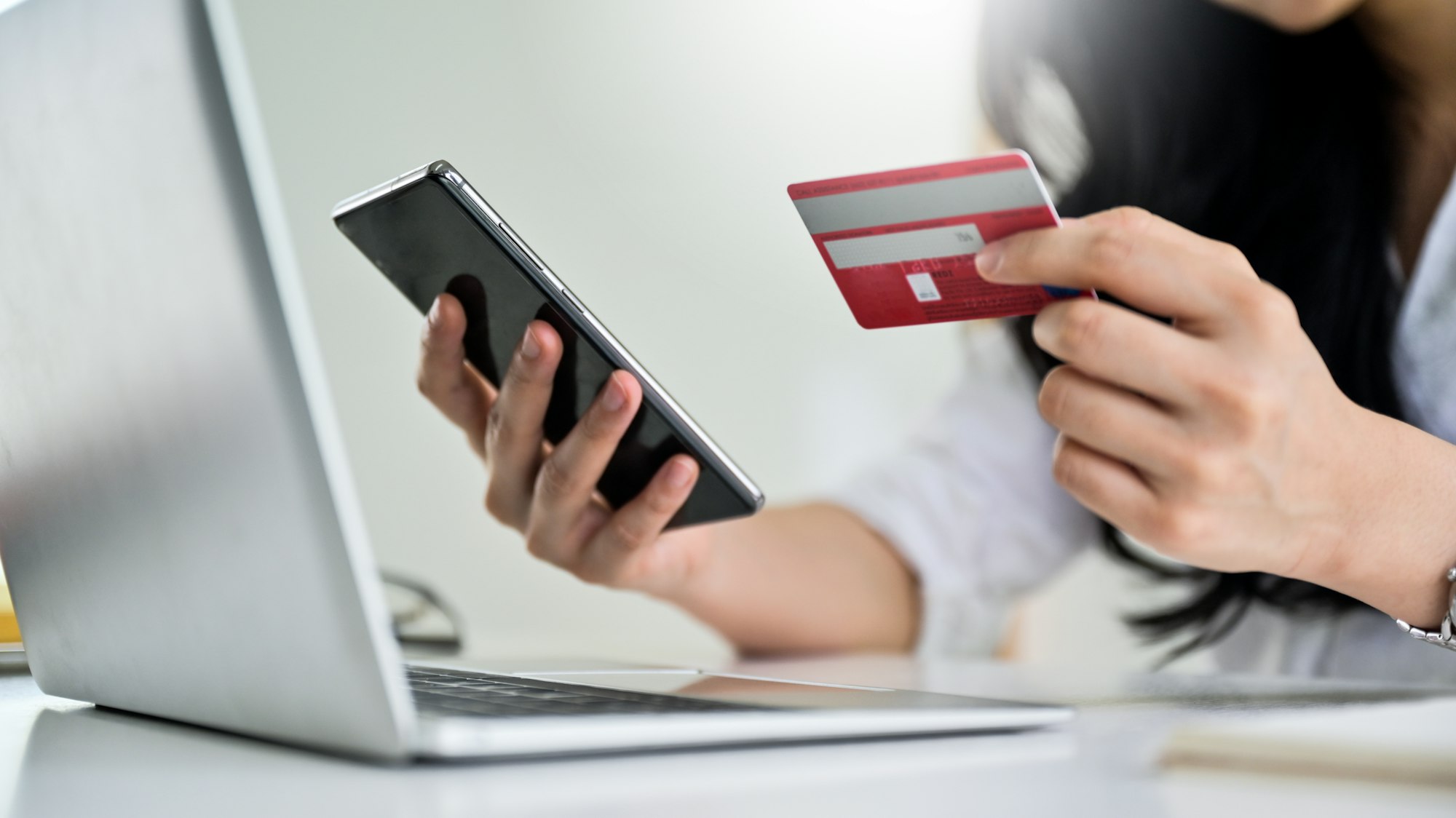 Young woman holding credit card and smartphone with laptop, Credit card payment.