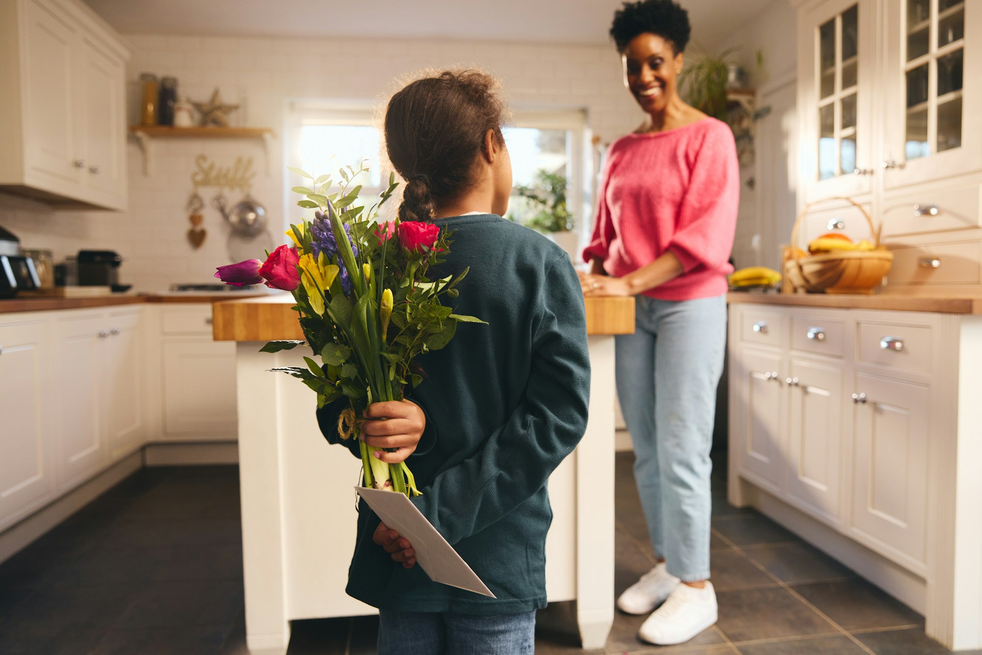 Boy hiding bouquet and card behind back on Mother's Day or Birthday