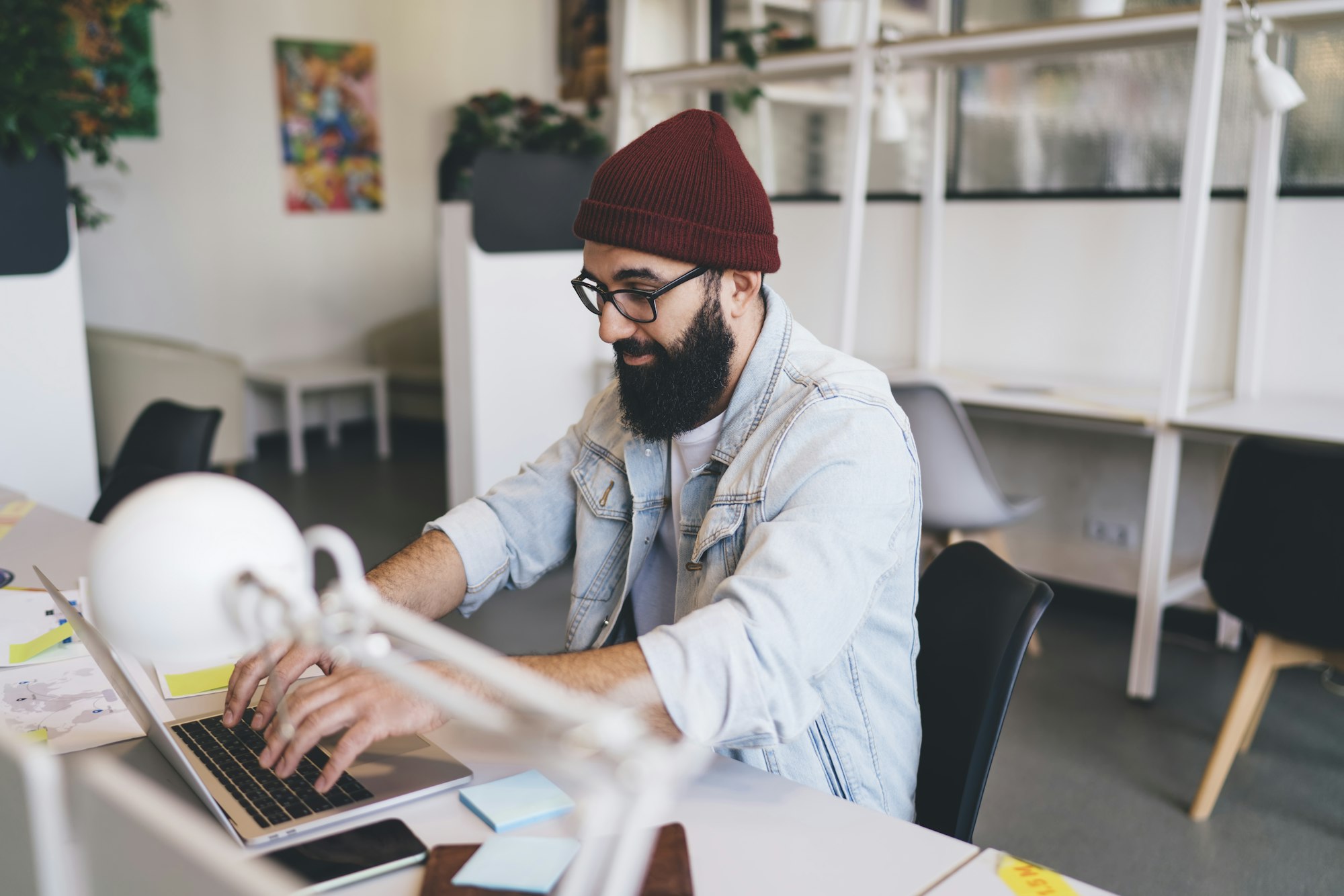 Concentrated bearded man typing on laptop keyboard in workspace