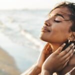 Peaceful black woman enjoying sun light at the beach