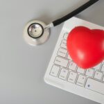 Stethoscope, red heart and computer keyboard. Online medical consultation concept.