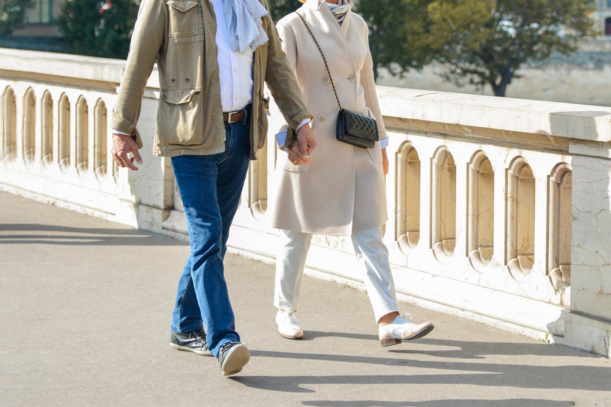 An elderly well dressed couple is walking in a Paris,France.