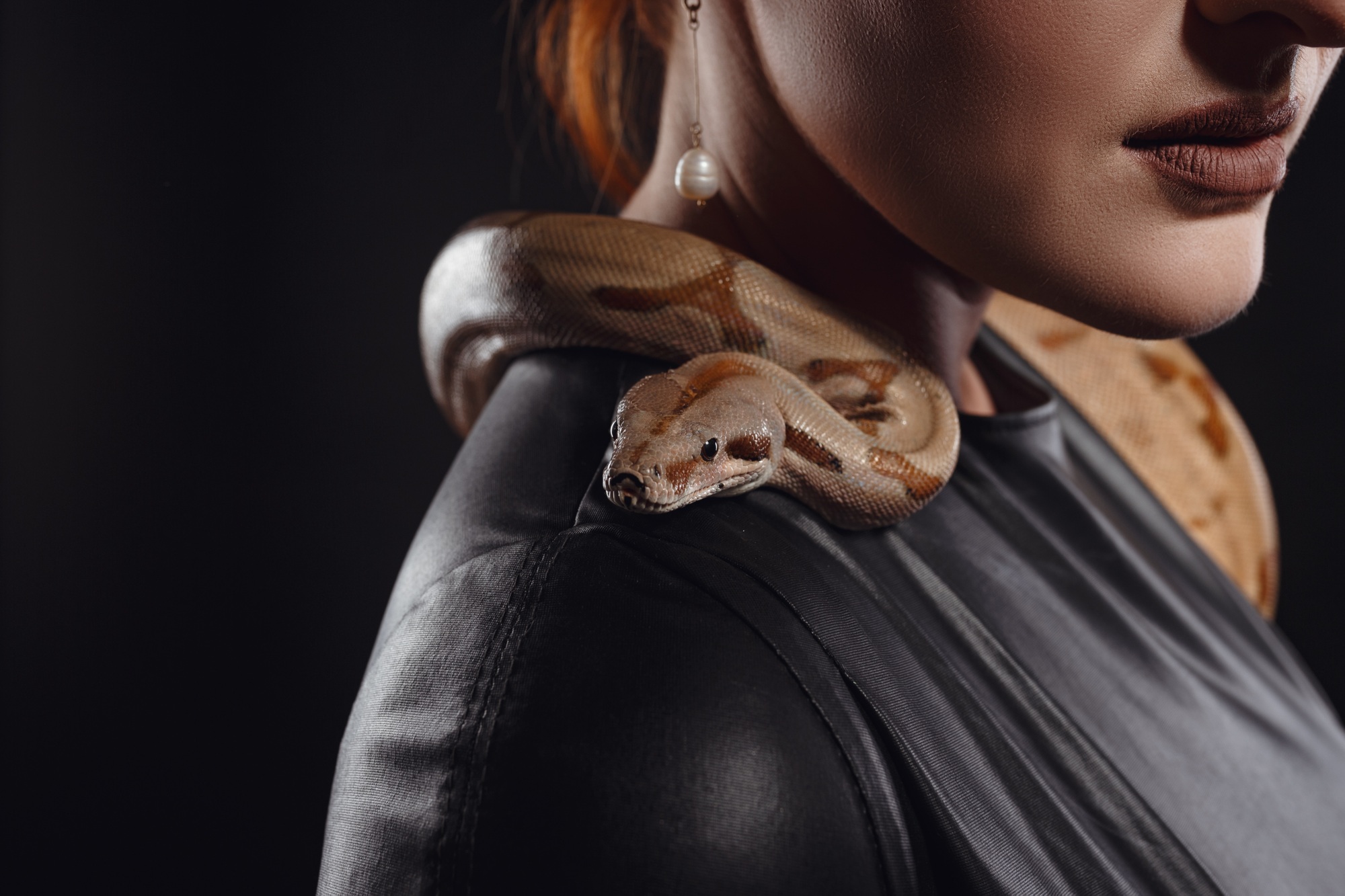 Close up portrait of sexy woman with snake in latex outfit